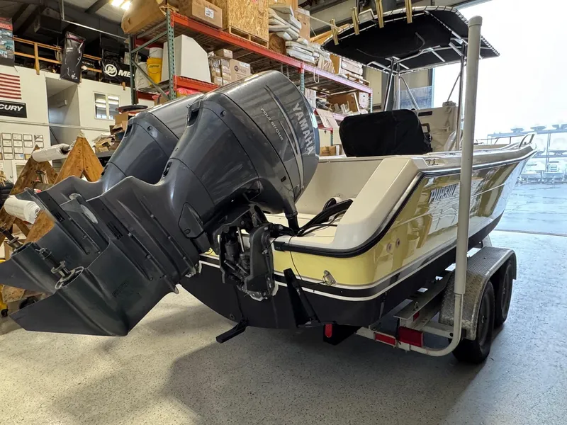 Slide: The Image of 2004 Pursuit 2470 CC boat on trailer with Yamaha outboard motor in a warehouse. - 8
