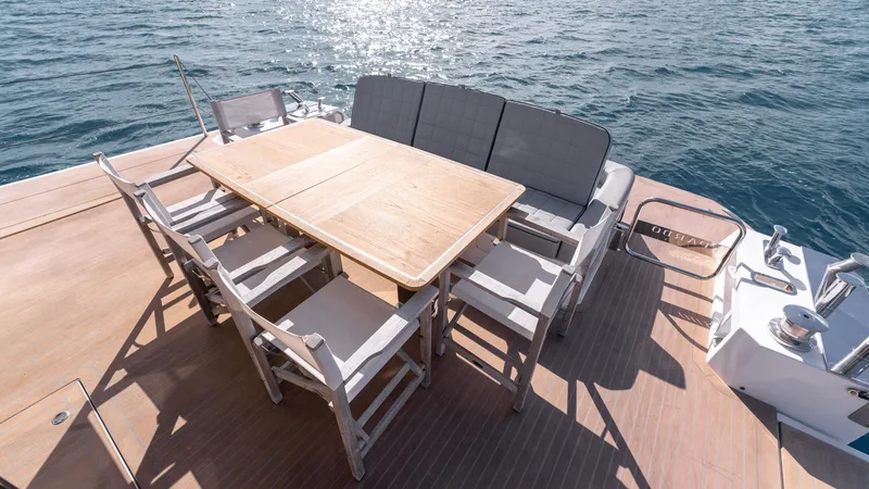 Slide: The Image of Outdoor dining area on 2024 Pardo Yachts E60, featuring wooden table and chairs, overlooking the sea. - 40