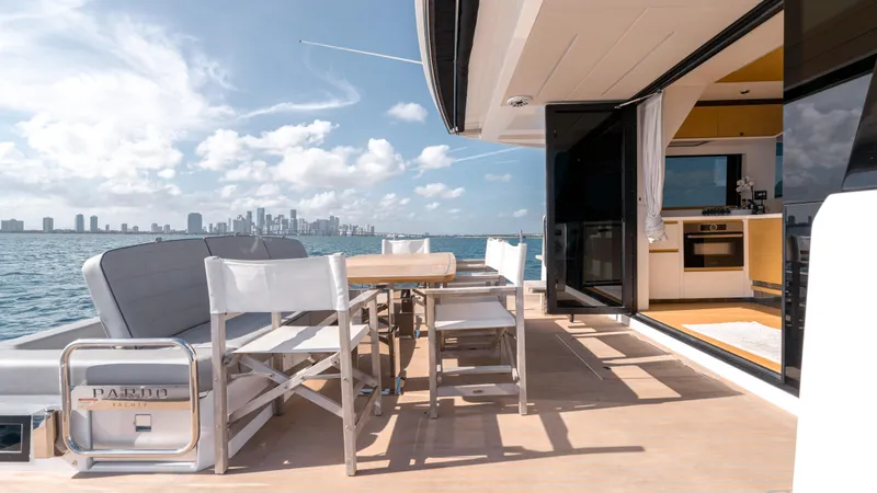 Slide: The Image of 2024 Pardo Yachts E60 deck with dining area, ocean view, and city skyline. - 48