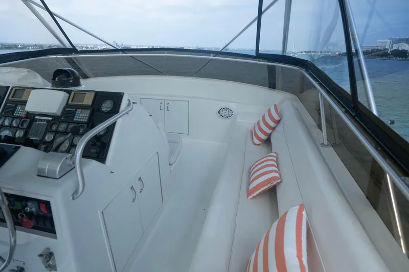 Slide: The Image of 1990 Hatteras 58 Convertible yacht helm with striped cushions and panoramic view. - 13