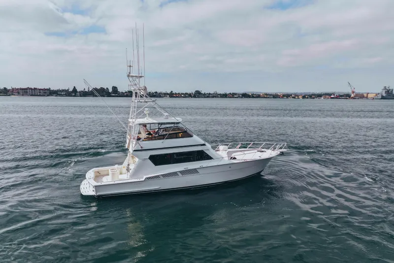 Slide: The Image of 1990 Hatteras 58 Convertible yacht cruising on open water under a cloudy sky. - 4