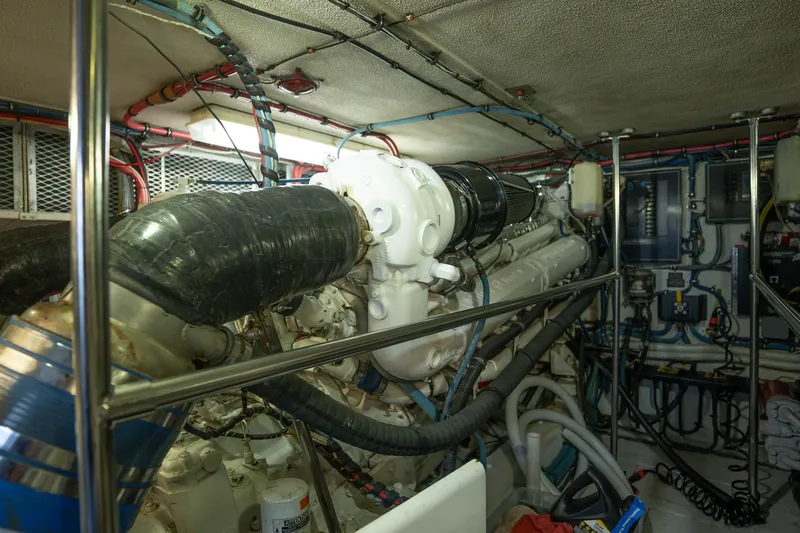 Slide: The Image of Engine room of a 1990 Hatteras 58 Convertible yacht, showcasing complex machinery and wiring. - 44