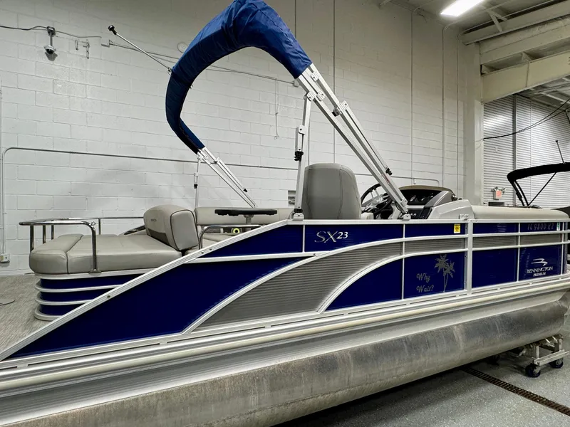 Slide: The Image of 2020 Bennington SXP 23 SSBXP pontoon boat with blue canopy in indoor storage. - 3