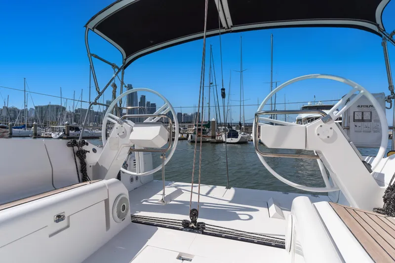 Slide: The Image of 2017 Elan E4 yacht cockpit with dual steering wheels in a marina setting. - 30