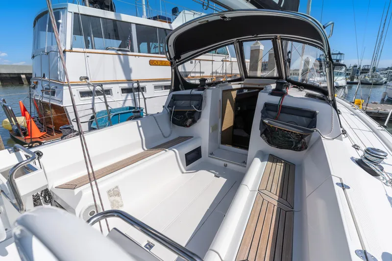 Slide: The Image of 2017 Elan E4 sailboat cockpit with seating, wood accents, and marina background. - 4