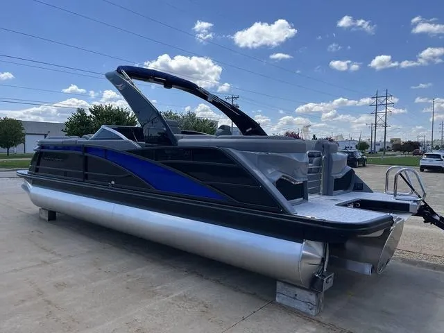 Slide: The Image of 2024 Bennington 25 QFBWA pontoon boat with sleek design, parked outdoors under a blue sky. - 4
