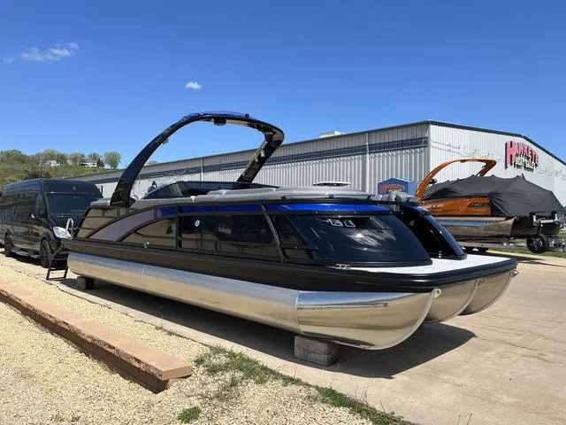 Slide: The Image of 2024 Bennington 25 QFBWA pontoon boat parked outdoors near a warehouse. - 6