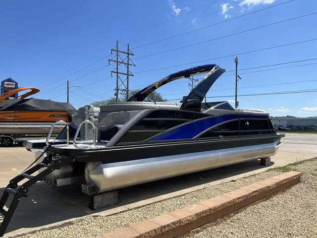 Slide: The Image of 2024 Bennington 25 QFBWA pontoon boat with sleek design, parked outdoors under clear sky. - 7