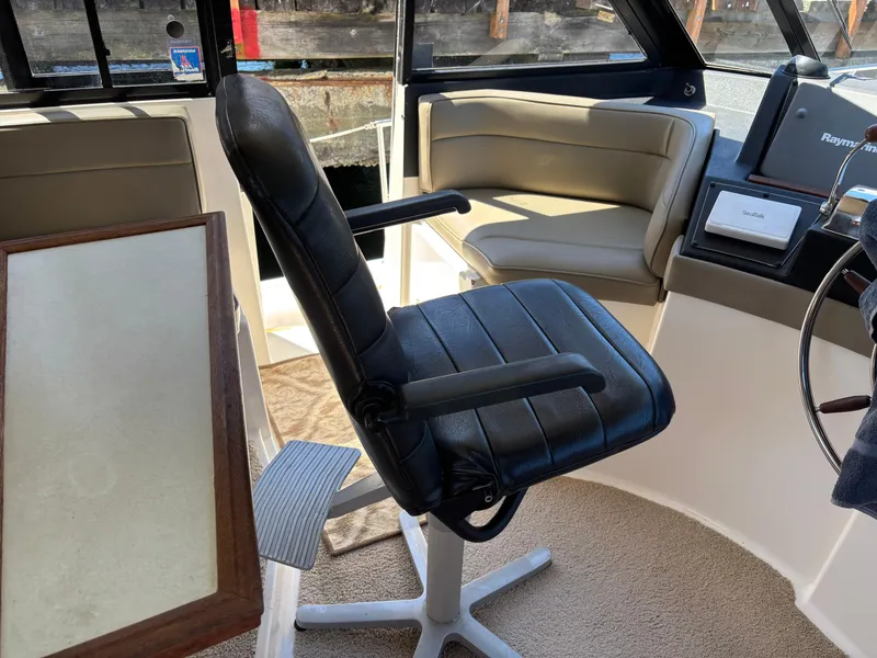 Slide: The Image of Interior of a 1994 Bayliner 4700 boat with black captain's chair and beige seating. - 11