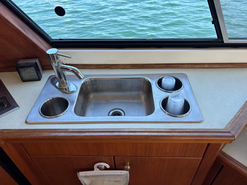 Slide: The Image of Bayliner 4700 yacht kitchen sink with faucet, 1994 model, overlooking water through window. - 16