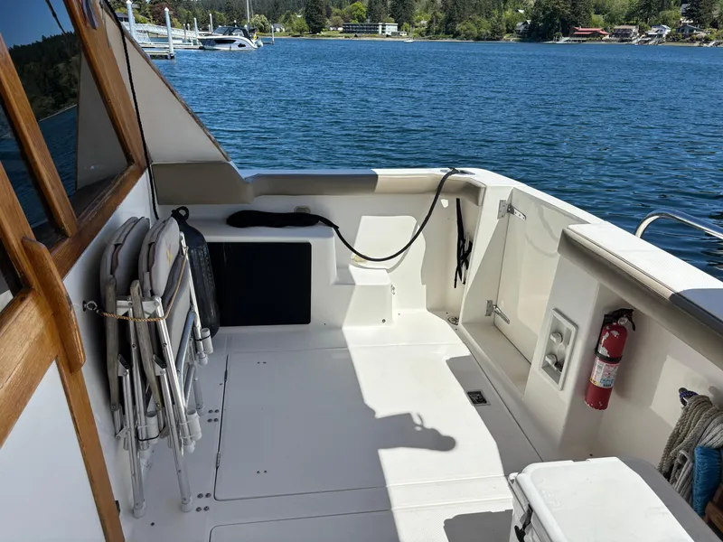 Slide: The Image of 1994 Bayliner 4700 boat deck with chairs, fire extinguisher, and scenic water view. - 2