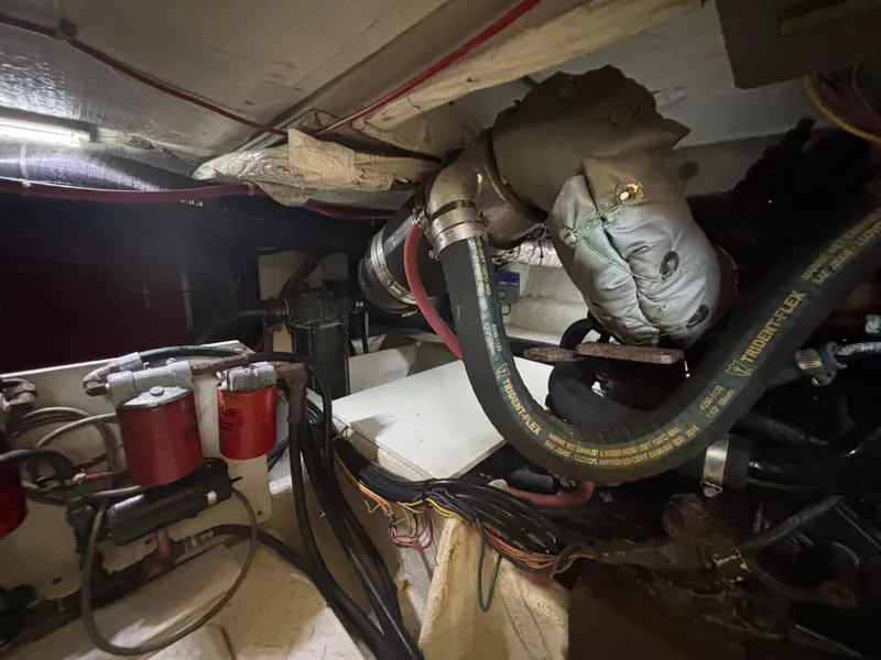 Slide: The Image of Engine room of a 1994 Bayliner 4700, showing hoses, filters, and mechanical components. - 25