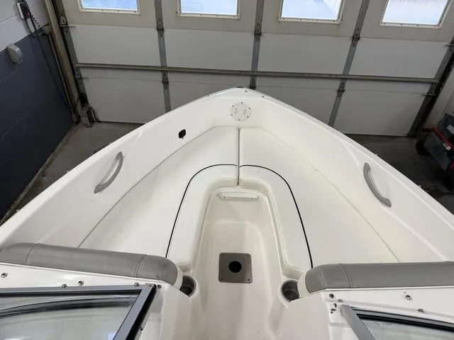 Slide: The Image of 2012 Bayliner 170SF boat interior, white seating, and storage area in a garage setting. - 12