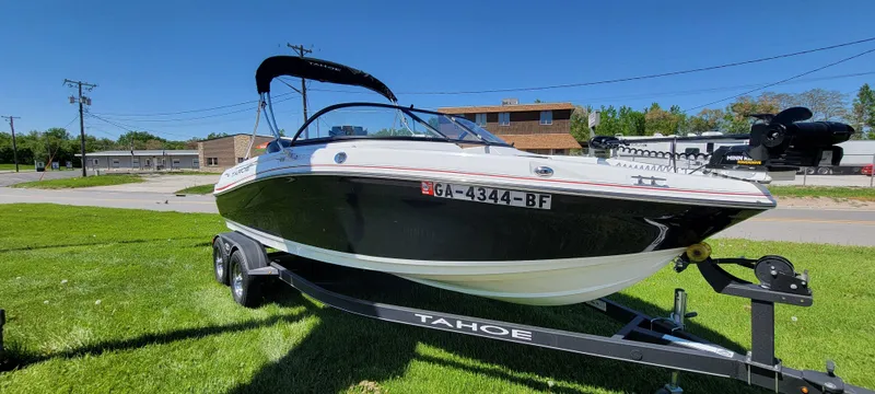 Slide: The Image of 2021 Bass Tracker TAHOE 550TF boat on trailer, parked on grass under clear blue sky. - 1