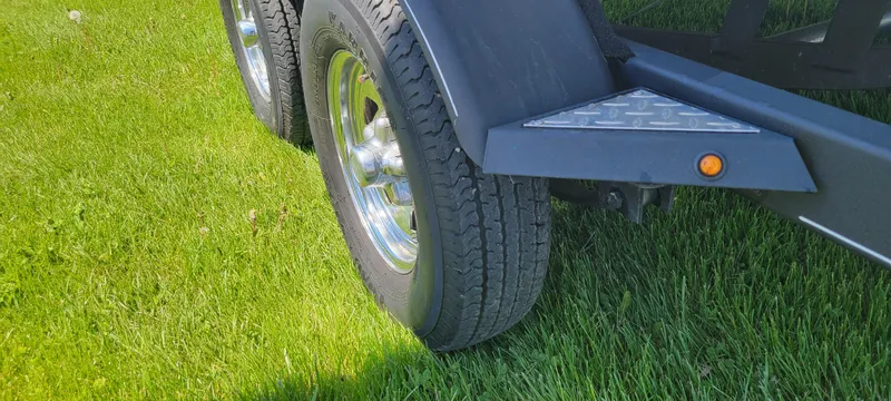 Slide: The Image of 2021 Bass Tracker TAHOE 550TF trailer tire on green grass. - 20