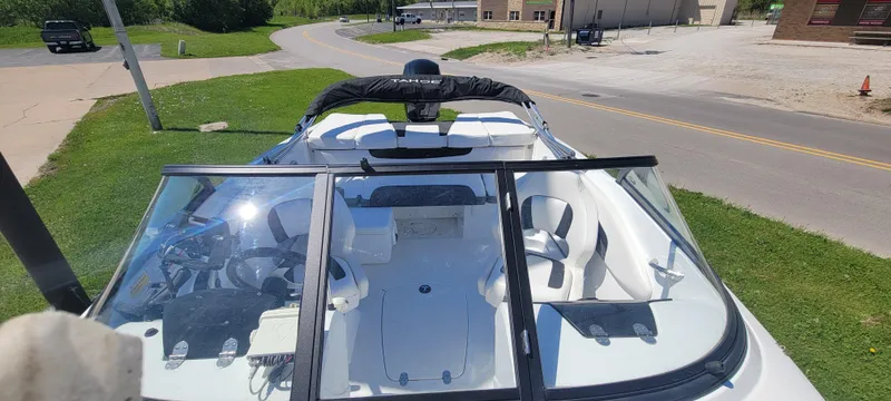 Slide: The Image of 2021 Bass Tracker TAHOE 550TF boat with open cockpit and windshield, parked on grass. - 5