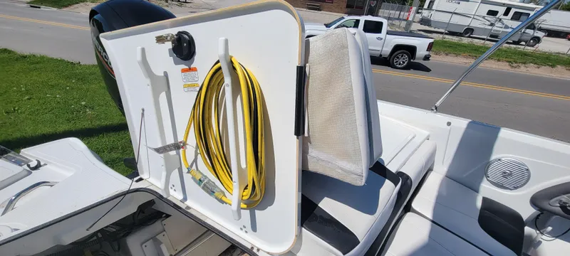 Slide: The Image of 2021 Bass Tracker TAHOE 550TF boat with storage compartment and yellow hose. - 6