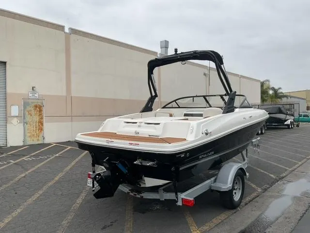 Slide: The Image of 2020 Bayliner VR4 Bowrider I/O on trailer, parked outdoors near industrial building. - 2