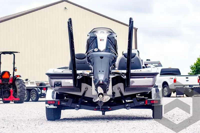 Slide: The Image of 2025 Caymas CX 21 PRO boat rear view, parked outdoors with trailers and vehicles nearby. - 6
