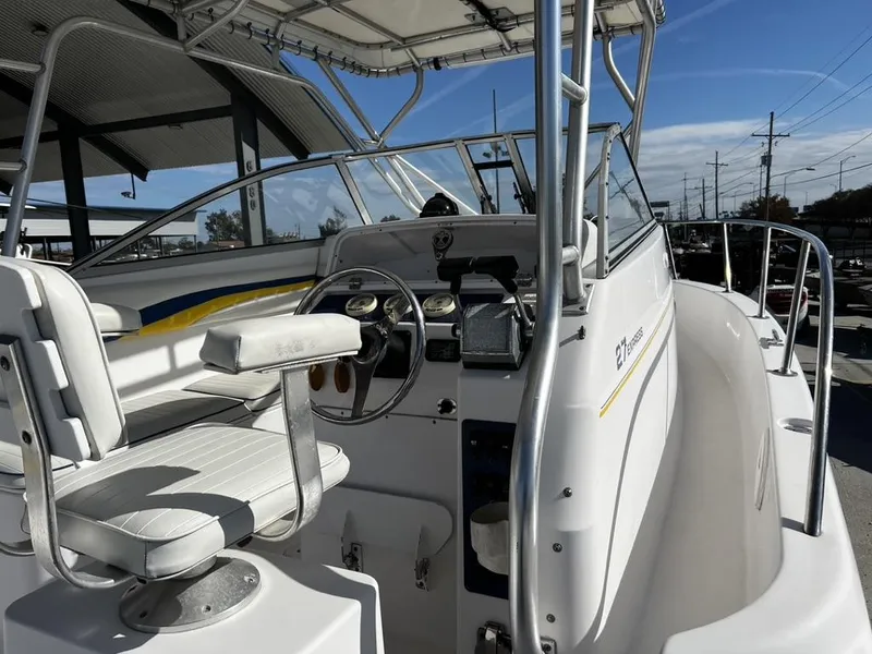 Slide: The Image of 2001 Pro-Line 27 Express boat cockpit with steering wheel and seating, under a clear blue sky. - 16