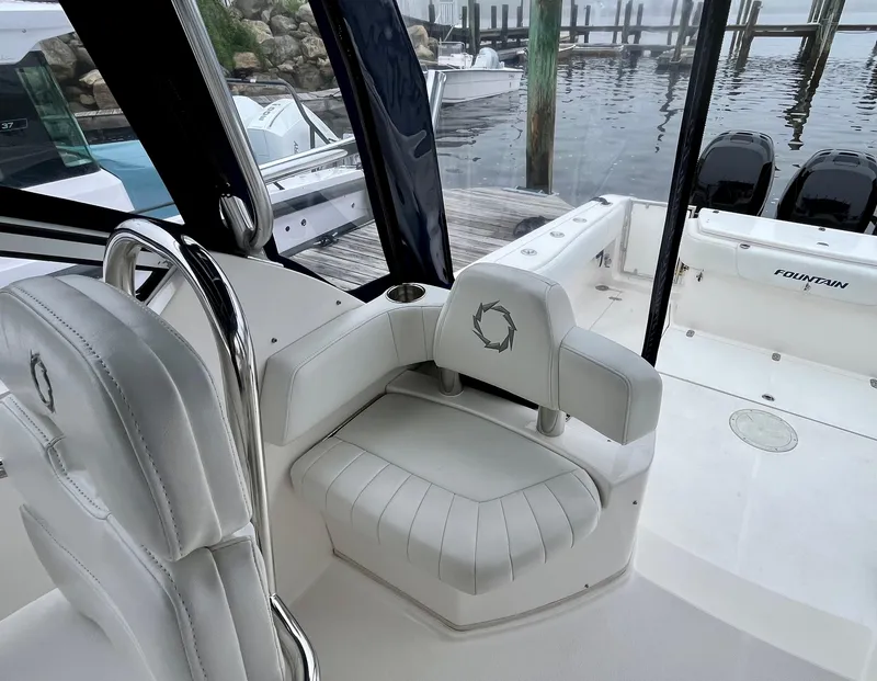 Slide: The Image of 2011 Fountain 38 Sportfish Cruiser interior with white seating, dockside view. - 19
