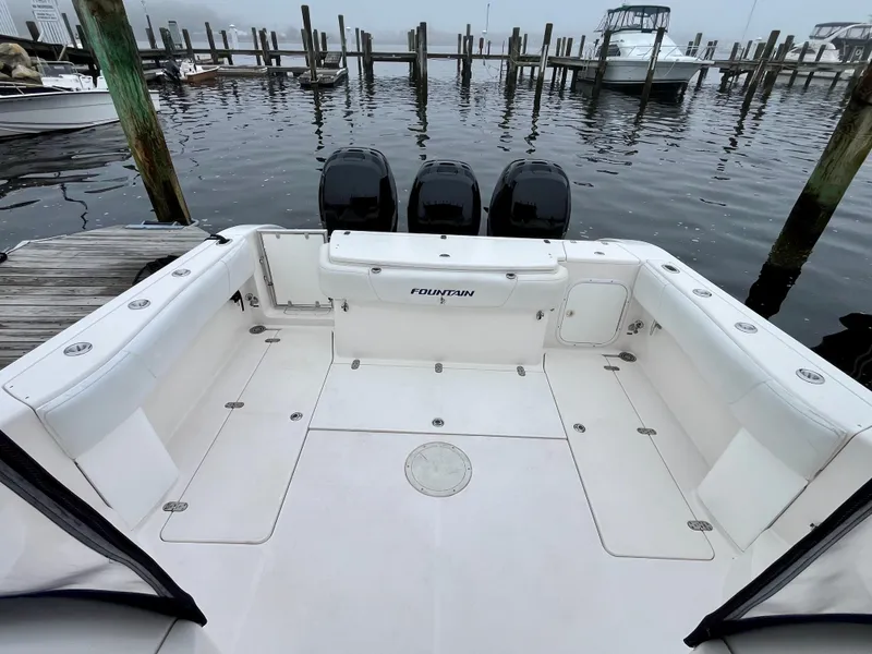 Slide: The Image of 2011 Fountain 38 Sportfish Cruiser at dock, featuring spacious deck and triple outboard engines. - 2