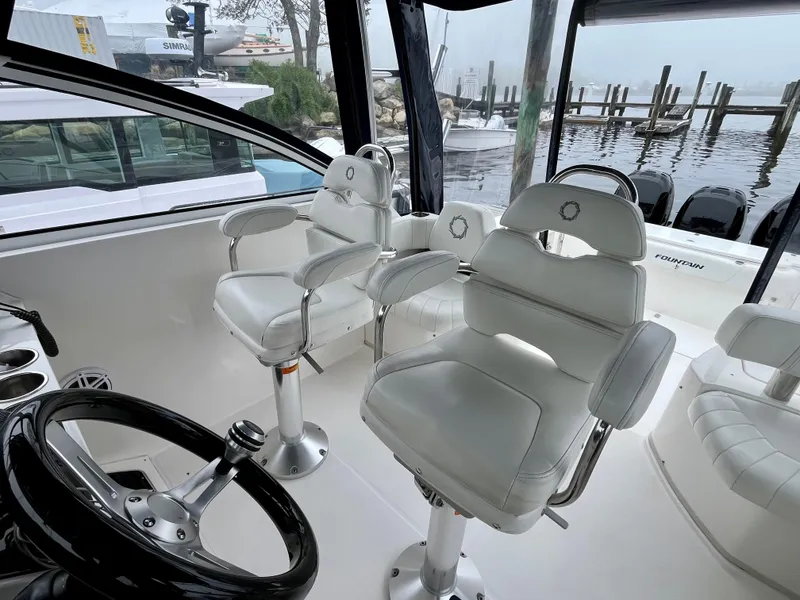 Slide: The Image of 2011 Fountain 38 Sportfish Cruiser interior with white captain chairs and steering wheel. - 20