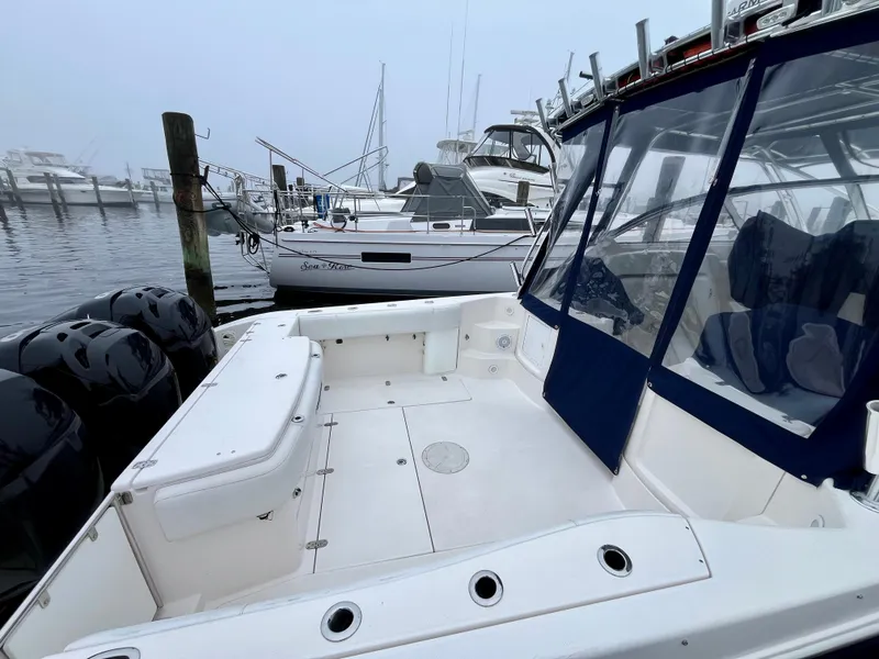 Slide: The Image of 2011 Fountain 38 Sportfish Cruiser docked, featuring spacious deck and multiple outboard engines. - 5