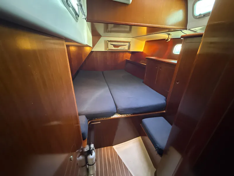 Slide: The Image of Cozy cabin interior of a 1997 Beneteau 50 sailboat with wooden finishes and blue cushions. - 31