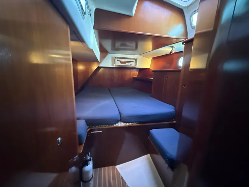 Slide: The Image of Cozy cabin interior of a 1997 Beneteau 50 sailboat with wooden finishes and blue cushions. - 34