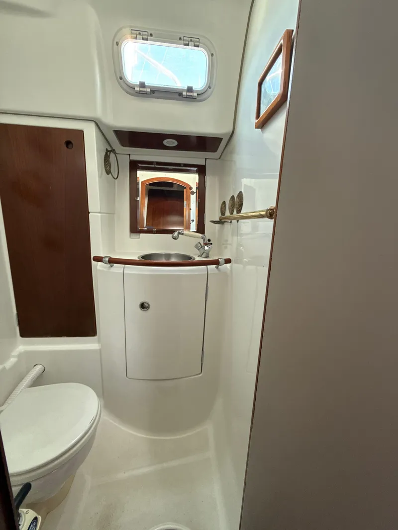 Slide: The Image of 1997 Beneteau 50 yacht bathroom with sink, toilet, and porthole window. - 36