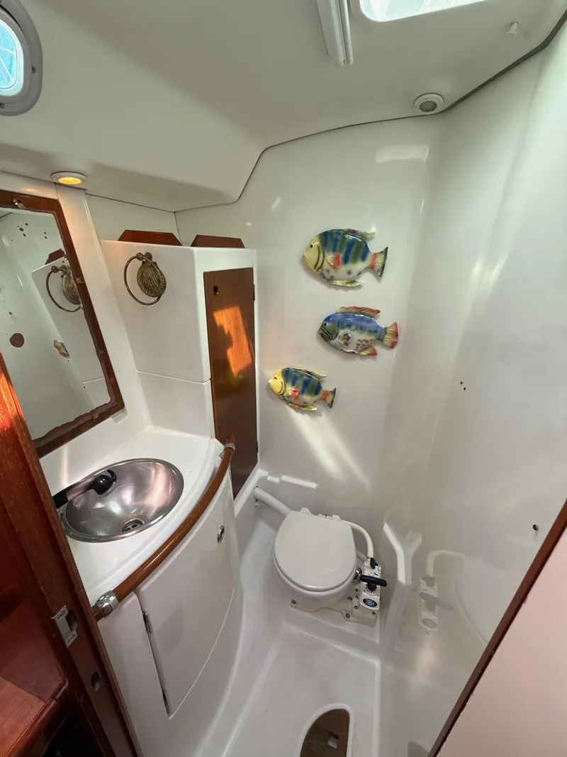 Slide: The Image of Beneteau 50 yacht bathroom, 1997 model, featuring sink, toilet, and decorative fish wall art. - 49