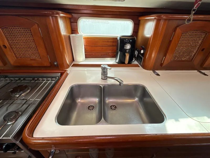 Slide: The Image of 1997 Beneteau 50 yacht kitchen with double sink, wooden cabinets, and stove. - 7