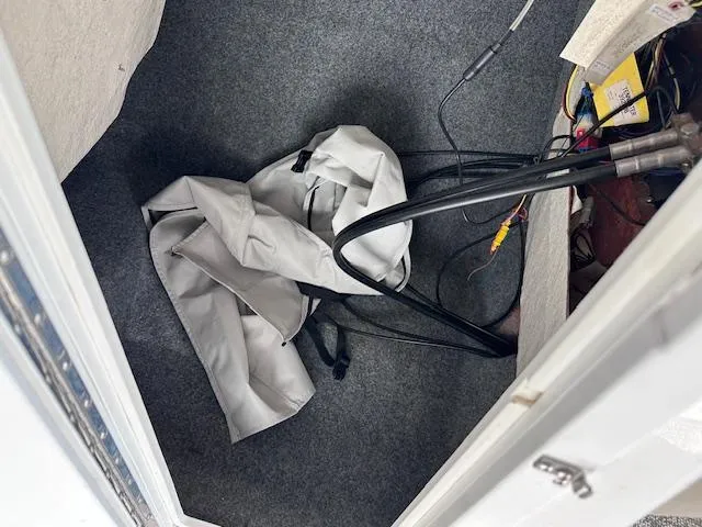 Slide: The Image of Storage compartment in a 2012 Yamaha Boats 242 Limited S with cables and a cover. - 26