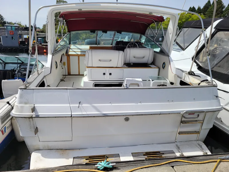 Slide: The Image of 1989 Sea Ray 340 Sundancer boat docked, featuring a spacious deck and maroon canopy. - 1