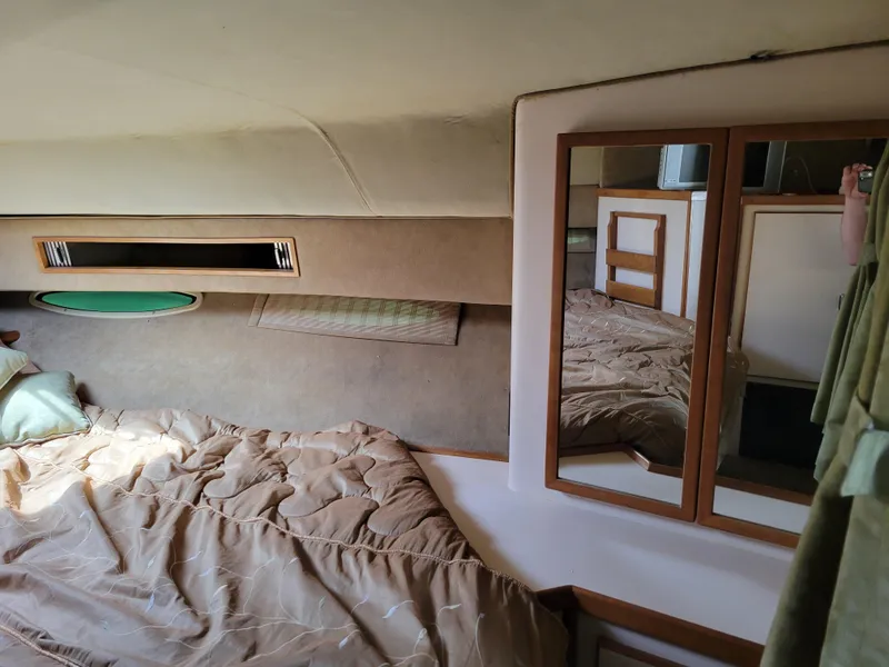 Slide: The Image of 1989 Sea Ray 340 Sundancer cabin interior with bed, mirror, and storage. - 27