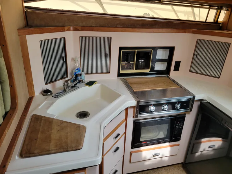 Slide: The Image of 1989 Sea Ray 340 Sundancer kitchen with sink, stove, and storage cabinets. - 28