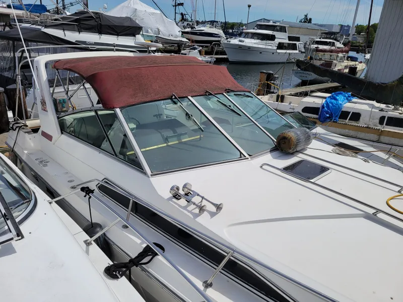 Slide: The Image of 1989 Sea Ray 340 Sundancer docked at marina, featuring red canopy and sleek design. - 3
