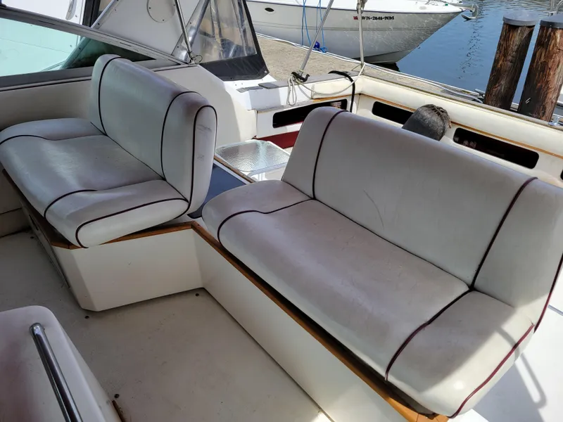 Slide: The Image of 1989 Sea Ray 340 Sundancer boat interior with white cushioned seating. - 9