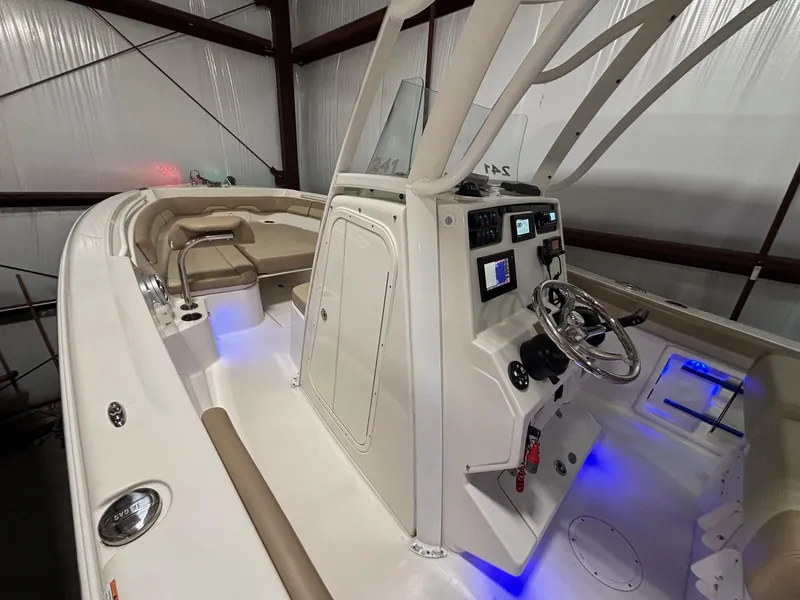 Slide: The Image of 2019 Sailfish 241 CC boat interior with modern console and seating, illuminated by blue lights. - 21