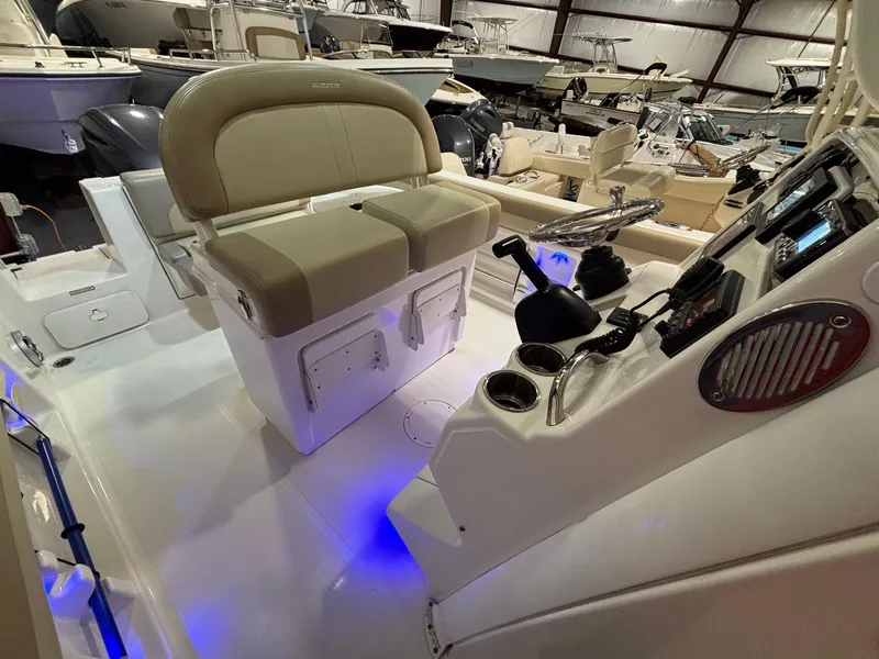 Slide: The Image of 2019 Sailfish 241 CC boat interior with helm, seating, and illuminated deck in a showroom. - 26