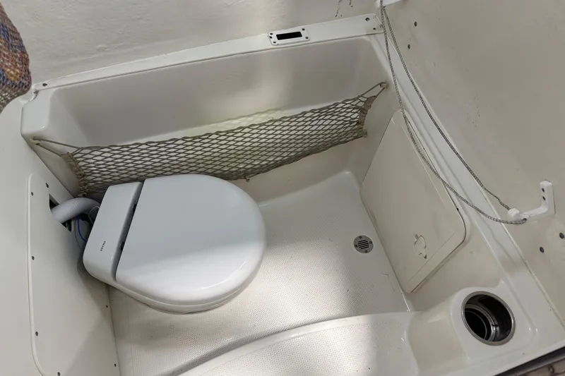 Slide: The Image of 2019 Sailfish 241 CC boat interior with compact marine toilet and storage net. - 47
