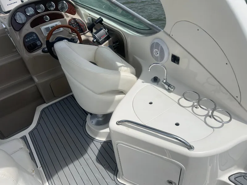 Slide: The Image of 2005 Sea Ray 280 Sundancer cockpit with helm, seating, and sink area. - 10