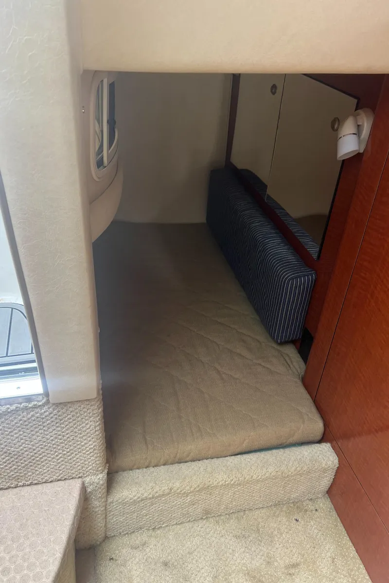 Slide: The Image of 2005 Sea Ray 280 Sundancer cabin interior with beige carpet and compact sleeping area. - 21