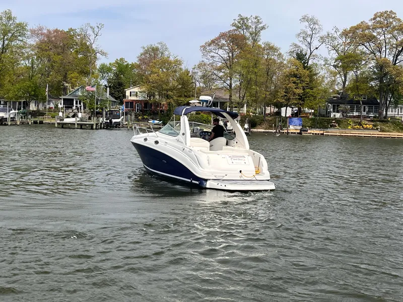 Slide: The Image of 2005 Sea Ray 280 Sundancer boat cruising on a calm lake near a wooded shoreline. - 4