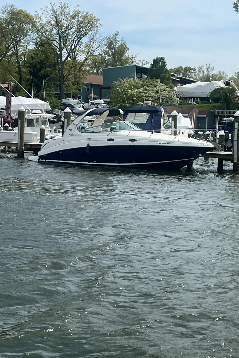 Slide: The Image of 2005 Sea Ray 280 Sundancer docked in a marina, surrounded by calm water and trees. - 7