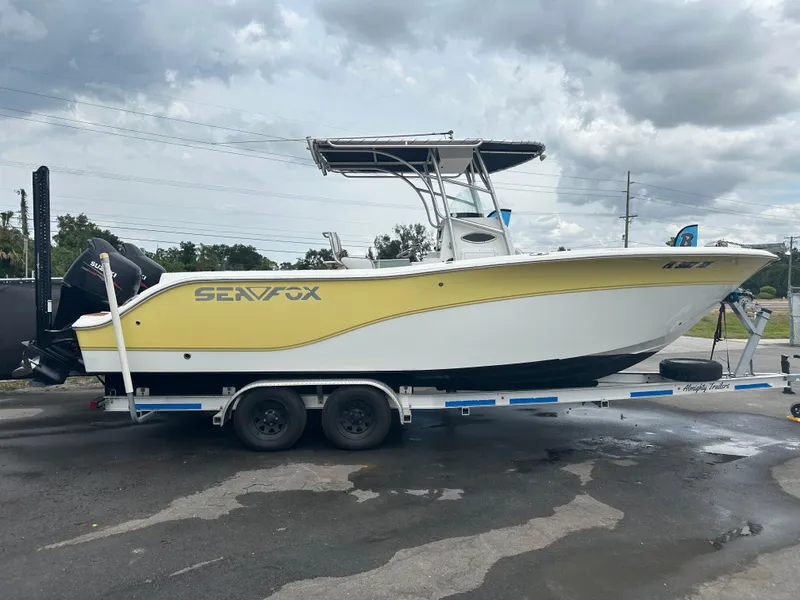 Slide: The Image of 2007 Sea Fox 256 CC boat on trailer, yellow and white design, parked outdoors. - 13