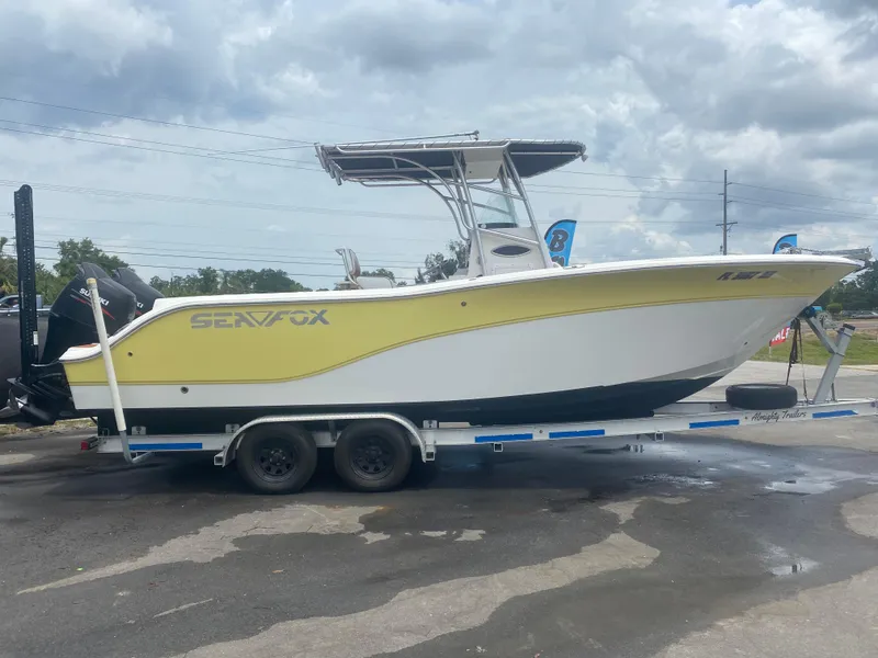 Slide: The Image of 2007 Sea Fox 256 CC boat on trailer, yellow and white design, parked outdoors. - 14