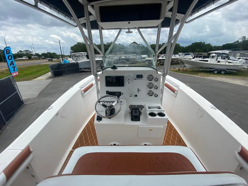 Slide: The Image of 2007 Sea Fox 256 CC boat cockpit with steering wheel, controls, and gauges, docked outdoors. - 21
