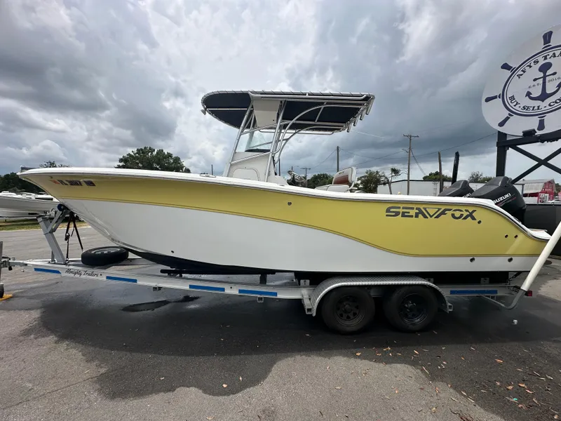 Slide: The Image of 2007 Sea Fox 256 CC boat on trailer, yellow and white hull, parked outdoors. - 8